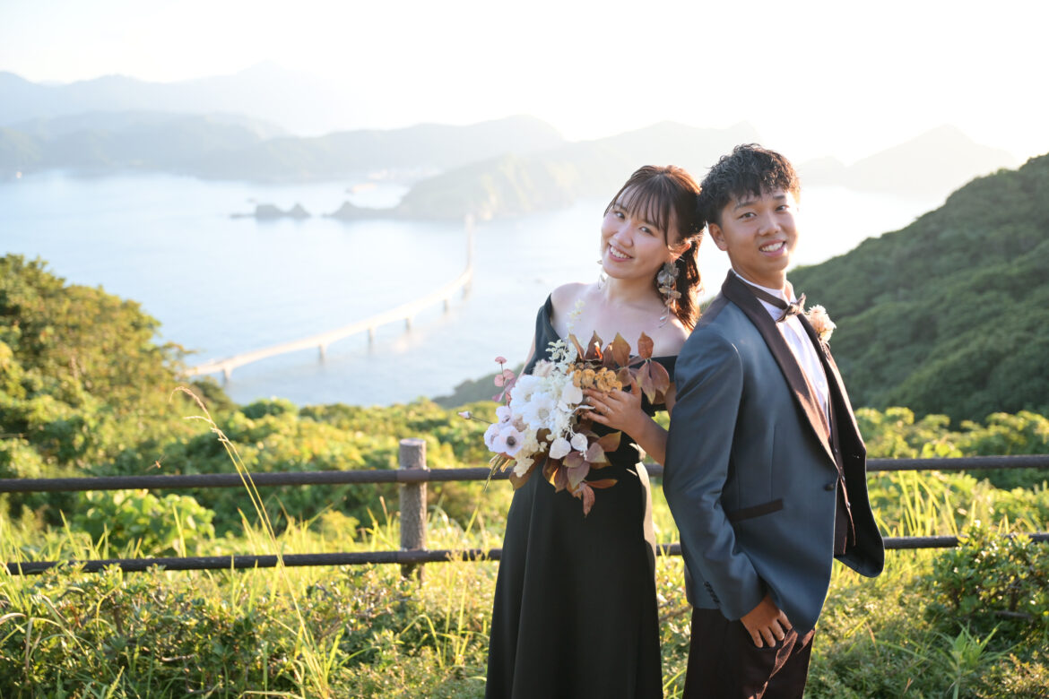 鹿児島・甑島の木の口展望所で甑大橋と海を背景に撮影した新郎新婦のフォトウェディング