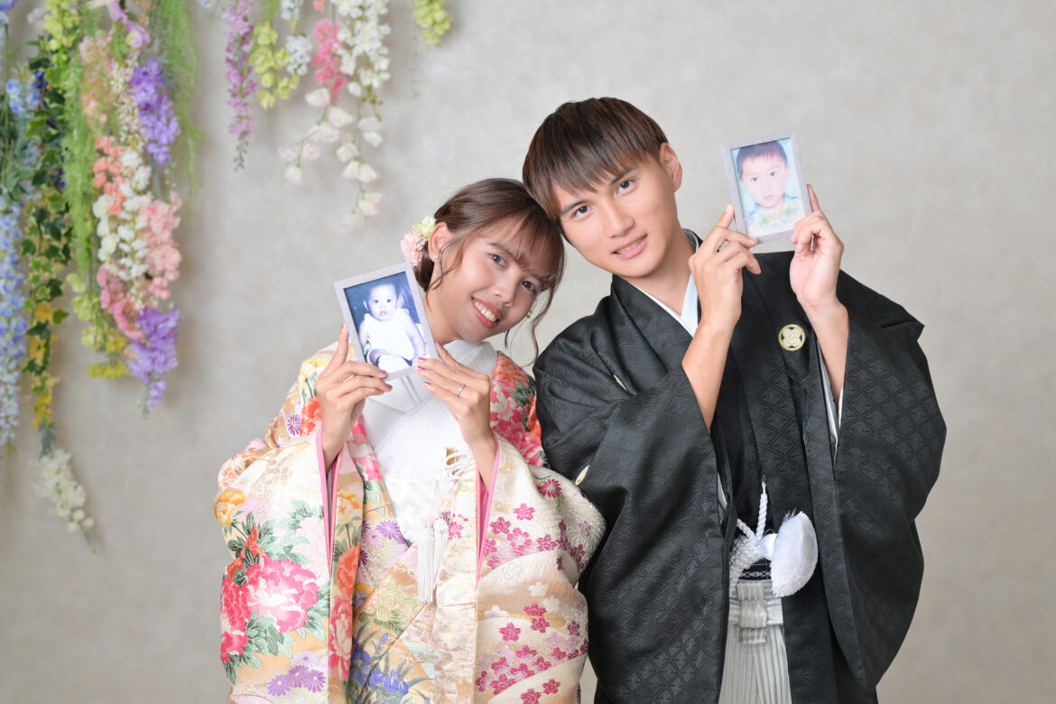 幼少期の写真を手にした新郎新婦の福岡店スタジオ和装前撮り