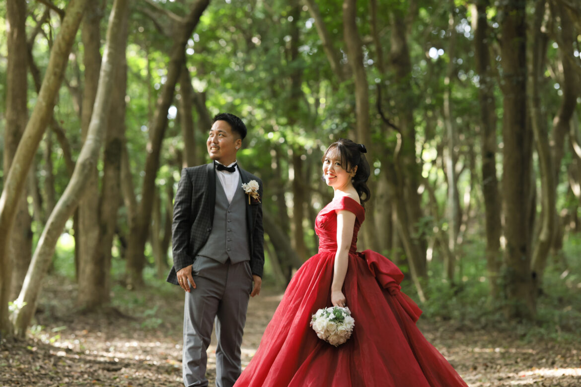 福岡の緑豊かな森で赤いカラードレスとタキシードを着た新郎新婦の前撮り写真